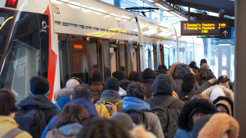 Crowds waiting to board a single-car light rail vehicle on the Ottawa O-Train system